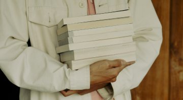 Person mit einem Stapel Bücher in den Händen
